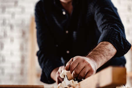 Carpenters hands planing a plank of wood with a hand planeの写真素材
