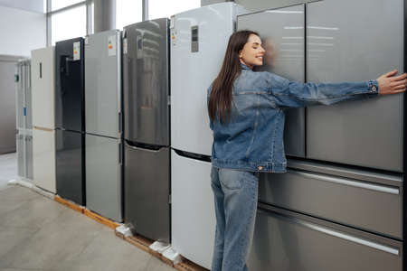 Young happy woman leaning on her new refrigerator in a mallの写真素材