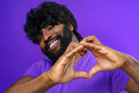 Black man in t-shirt showing heart with handsの写真素材
