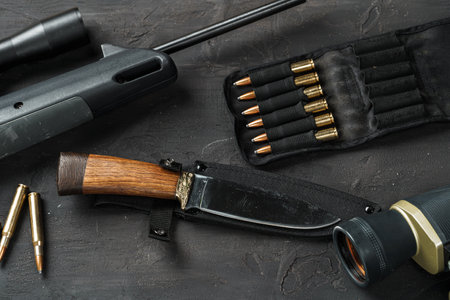 Hunting rifle and cartridges on dark wooden background