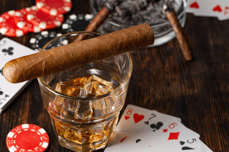 Playing poker with whiskey and cigars on table