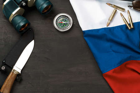 Hunting knife, binoculars and cartridges with russian flag on black background, top viewの写真素材