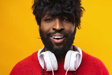 Young african american man with white headphones against yellow backgroundの写真素材