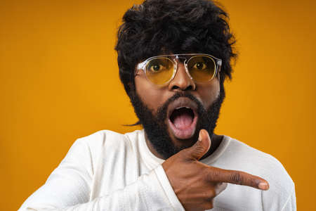 Cheerful african american man pointing finger at copy space