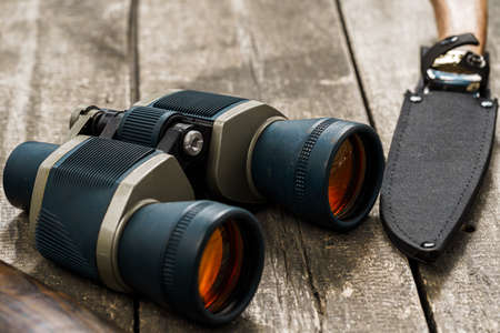 Hunting equipment binoculars on wooden background close up