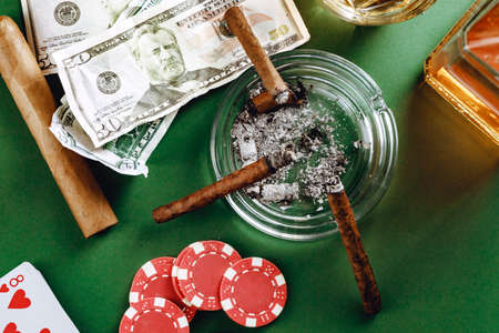 Glass of whiskey, cigar, playing cards and chips on green backgroundの写真素材