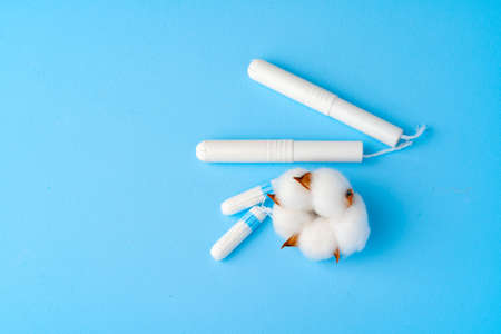 Female medical tampons and cotton flower on blue paper backgroundの写真素材