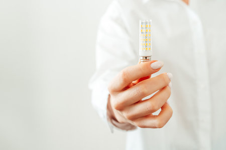 Woman in white shirt holding light bulb in handの写真素材