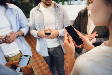 Diverse young people colleagues working on mobile phones together in officeの写真素材
