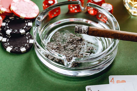 Cuban cigar, whiskey glass and chips on tableの写真素材