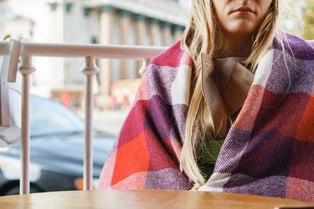 Unrecognizable woman covered with checkered plaid sitting in outdoor cafeの写真素材