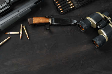 Hunting rifle and cartridges on dark wooden background
