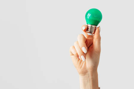 Female hand holding light bulb against gray background