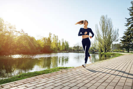 Athletic fit young woman jogging early in the morning in parkの写真素材