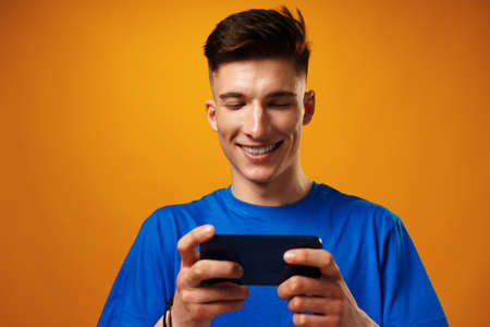Young man using smartphone against yellow background