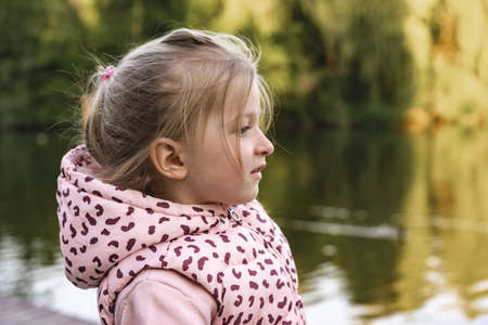 Little girl sitting in park near the lake