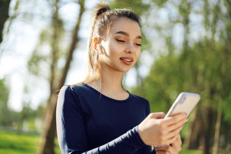 Young woman turns on music for running on her smartphone outdoorsの写真素材