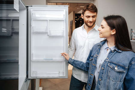 Young couple selecting new refrigerator in household appliance storeの写真素材
