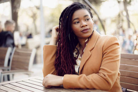 Portrait of a young black woman sitting at the table in cafeの写真素材