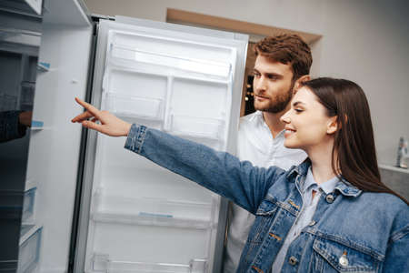 Young couple selecting new refrigerator in household appliance storeの写真素材
