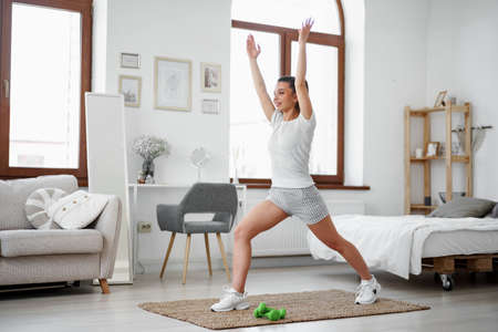 Young fitness girl doing sport exercises at her living room at homeの写真素材