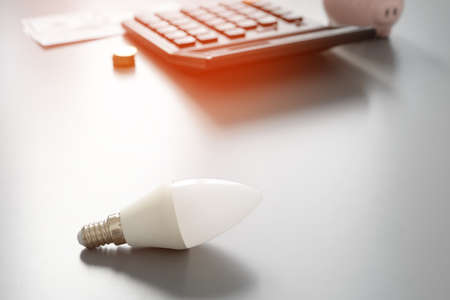 Light bulb and calculator on gray tableの写真素材