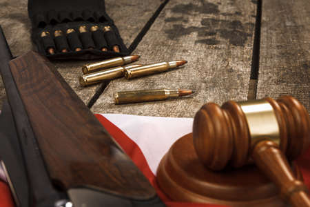 Wooden judge gavel and hunting rifle over USA flag on wooden backgroundの写真素材