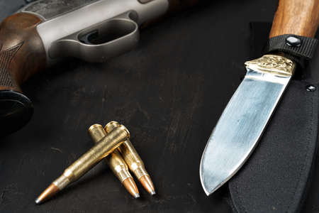 Hunting rifle and cartridges on dark wooden background