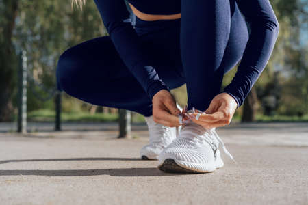 Close up of young woman tying laces on her sports shoesの写真素材