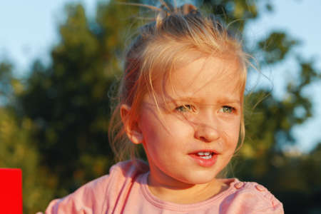 Close up portrait of a little blonde girl on a summer day