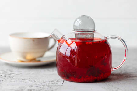 Berry tea in glass teapot on gray surfaceの写真素材