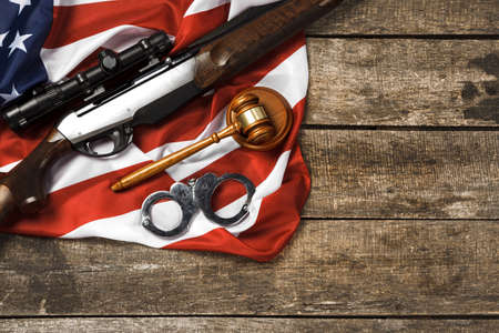 Wooden judge gavel and hunting rifle over USA flag on wooden backgroundの写真素材