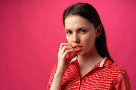 Studio portrait of beautiful young woman thinking against pink backgroundの写真素材