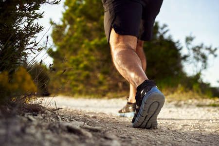 Close up of male muscular legs running up the hillの写真素材