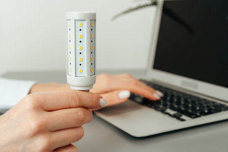 Female hand holding a light bulb above the table