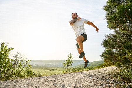 Young muscular male athlete running up the hill