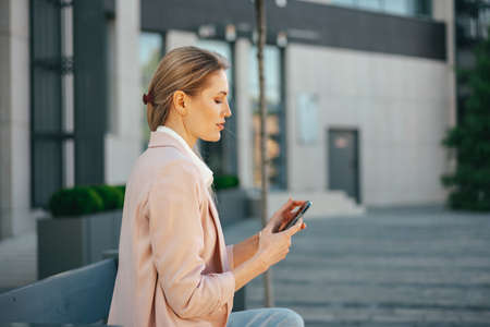 Close up of a businesswoman using smartphone outdoors in the city