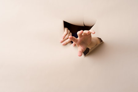 Female hands tearing a hole in beige banner paperの写真素材