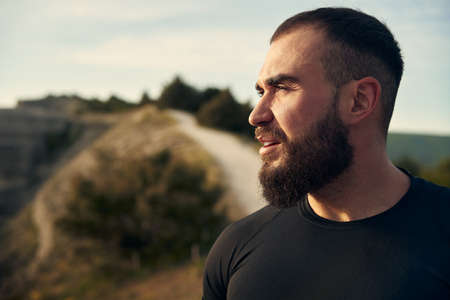 Young bearded man portrait outdoors in the mountains