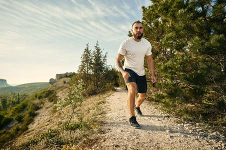 Young muscular male athlete running up the hill
