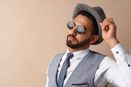 Cool egyptian man in hat and sunglasses posing against beige backgroundの写真素材