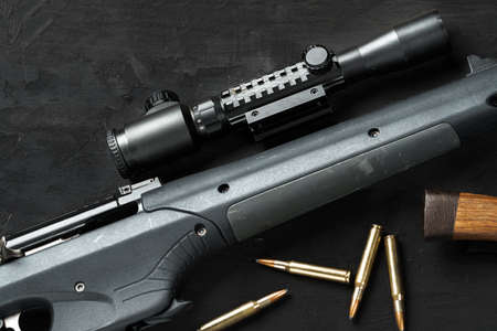 The optical sight and shotgun on wooden backgorund