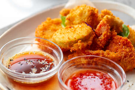 Deep fried chicken nuggets with sauce served on table