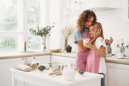 Portrait of a teen girl with her mother at home in kitchenの写真素材