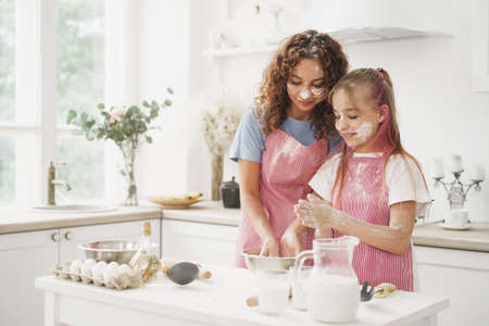 Mother and daughter having fun while cooking dough in kitchenの写真素材