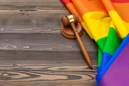 Woden judge mallet symbol of law and justice with lgbt flag in rainbow colours on wooden backgroundの写真素材