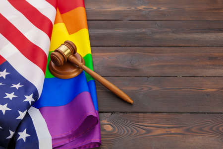 Woden judge mallet symbol of law and justice with lgbt flag in rainbow colours on wooden backgroundの写真素材