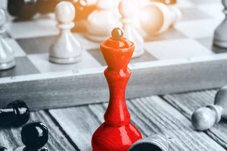 Chess pieces on a wooden chessboard against a dark backgroundの写真素材