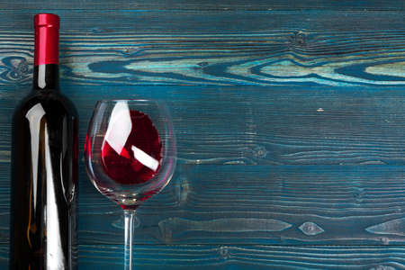 glass and bottle with red wine on wooden background, top view
