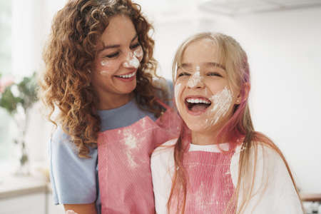 Mother and daughter having fun while cooking dough in kitchen